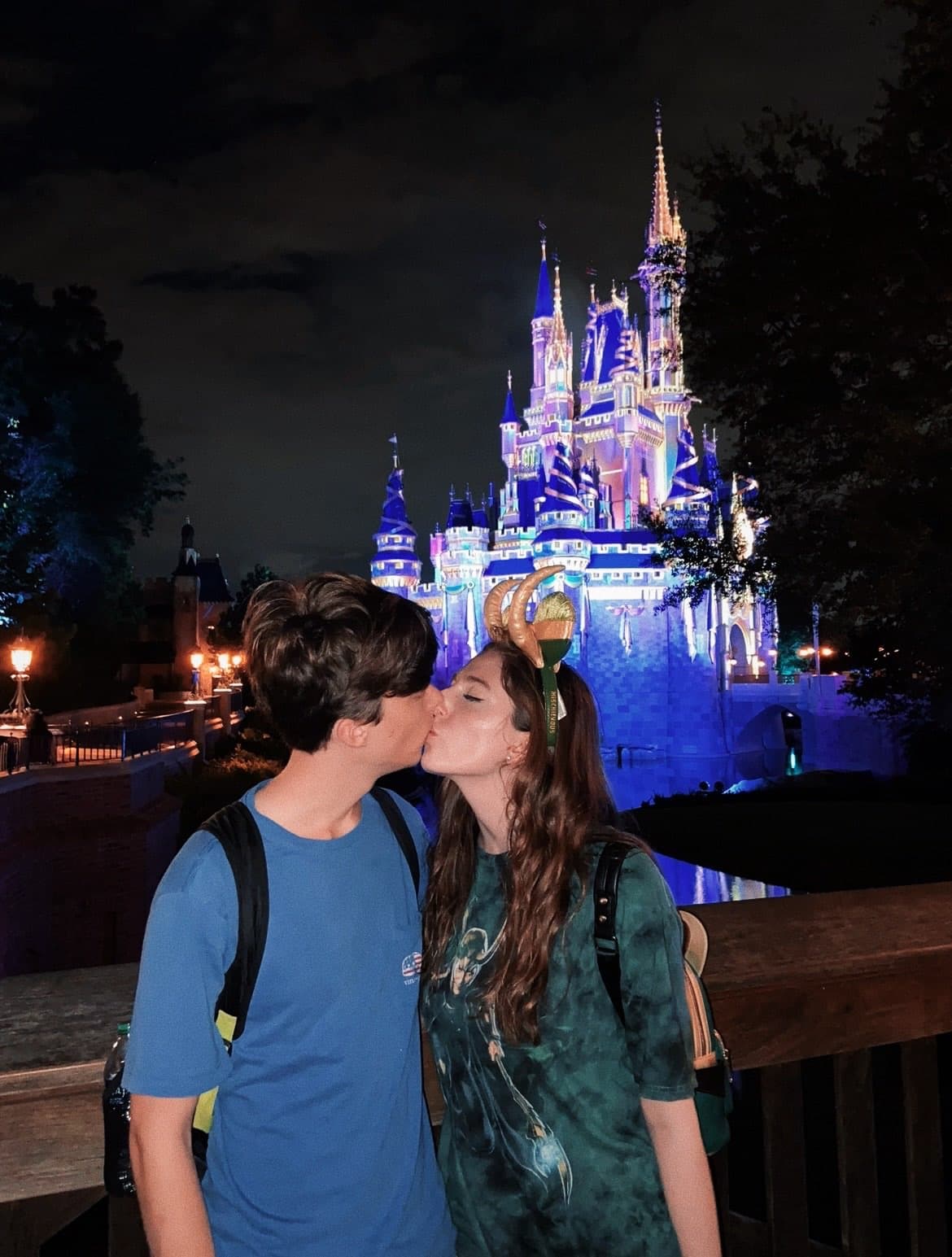 Max and Alex kissing in front of the Disney castle.